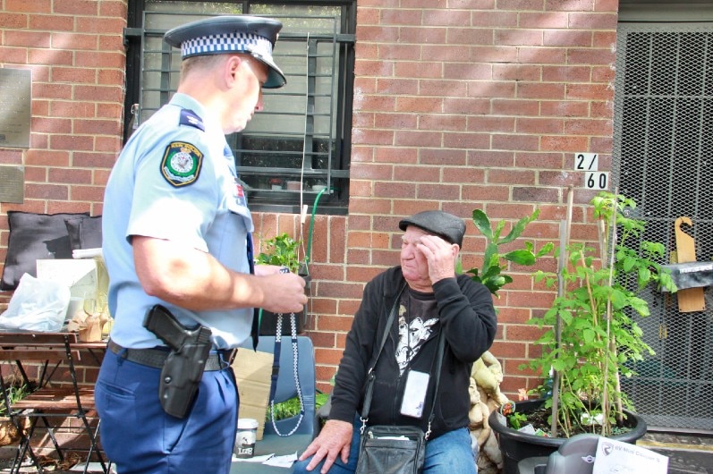 A police officer with an elderly man who is sitting down.