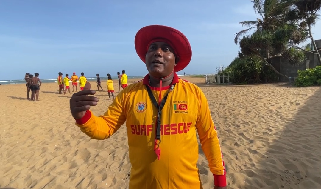 homem de uniforme vermelho e amarelo na praia.