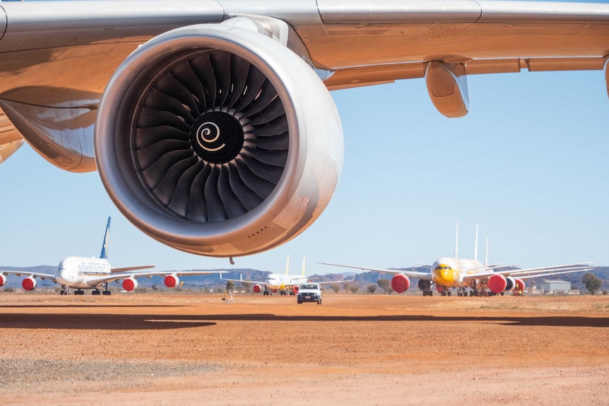 Many planes can be seen under the wing of a large aircraft.