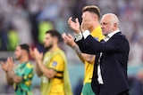Australian coach Graham Arnold applauds fans after the Socceroos lose a match at the World Cup.