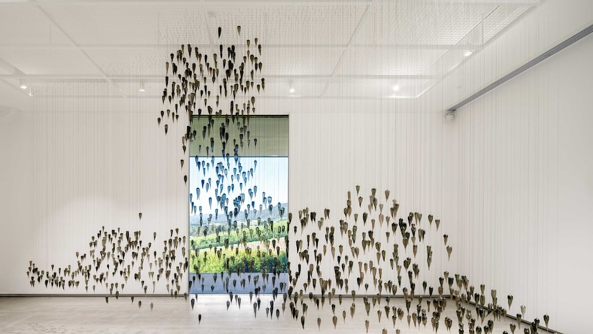 A sculpture made of a thousand glass yams hanging from the ceiling in the shape of a mushroom cloud by Yhonnie Scarce
