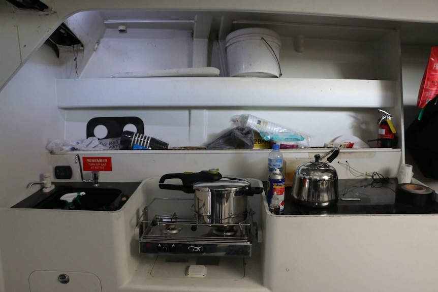 The kitchen on the boat which includes a small stove and sink