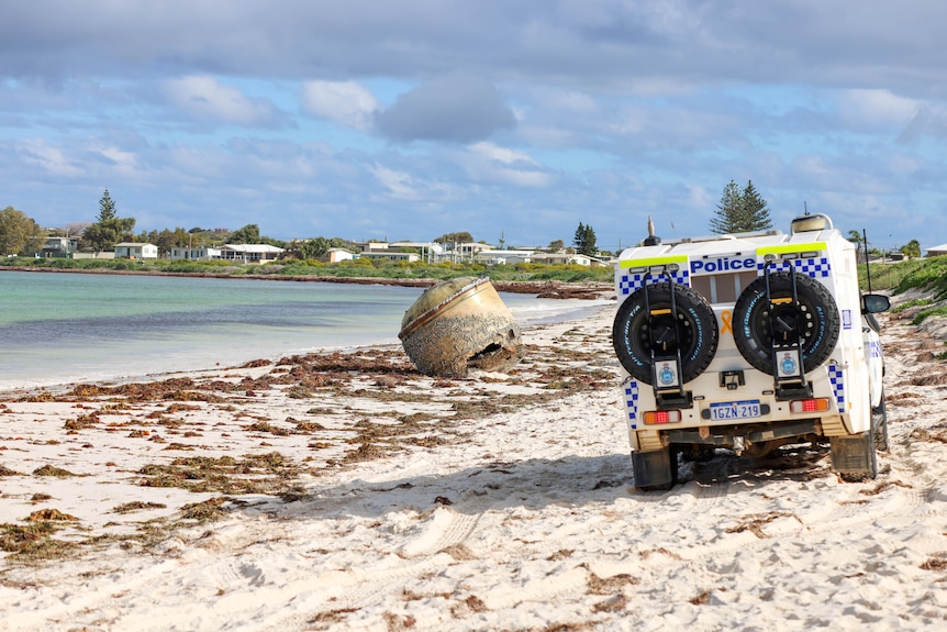 Rear of a police 4WD with a large sphere object on the beach