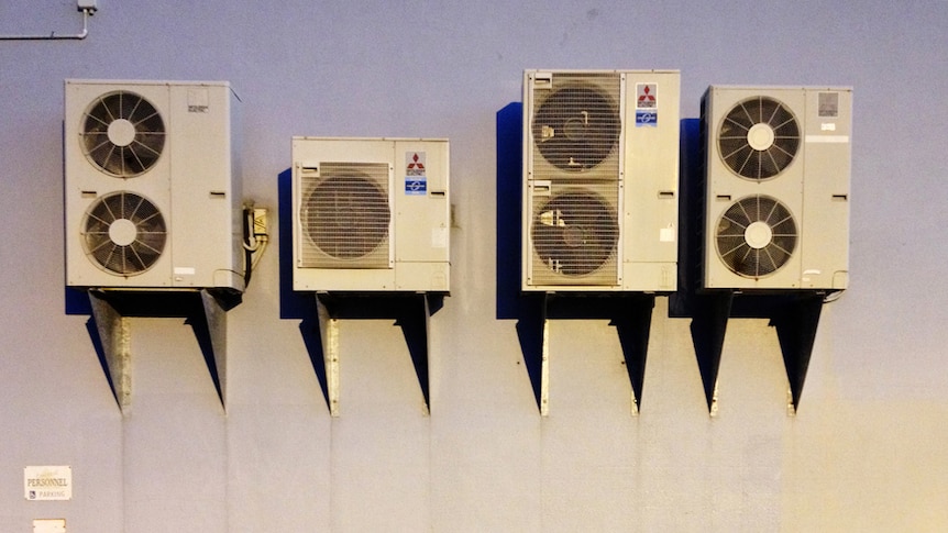 Four air conditioning units on the outside of a building.