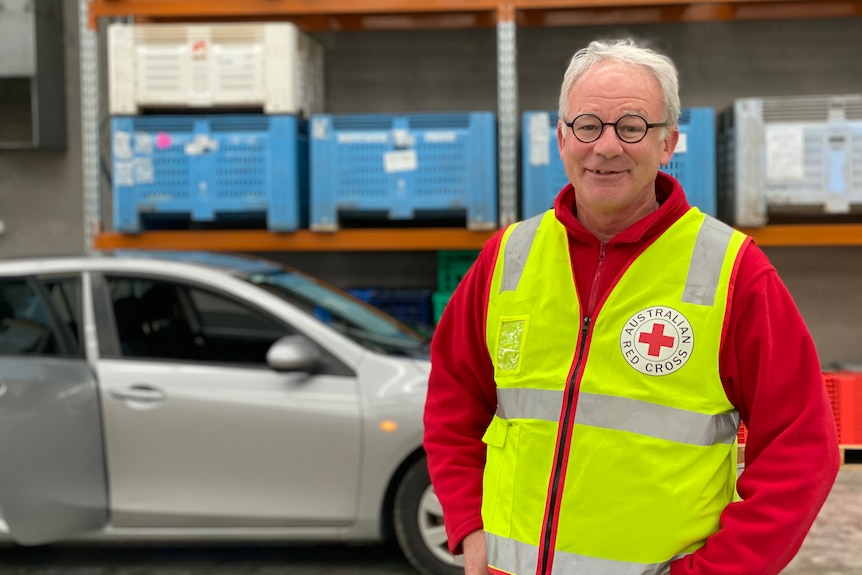 John smiles and looks to the camera while wearing a red turtleneck and yellow hi vis vest.