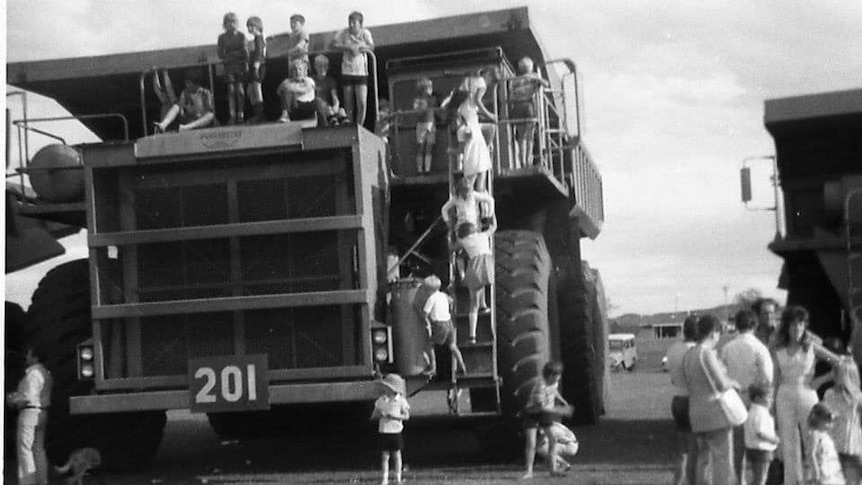 black and white photo of kids on a huge truck on the oval
