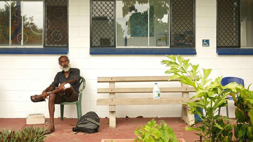 a photo of a long grasser sitting on a seat next to a bench.