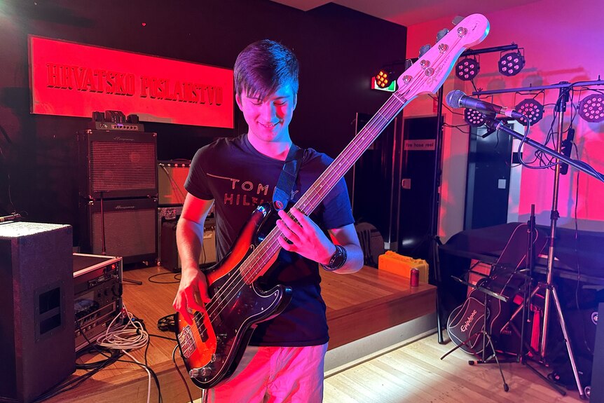 Teenage boy playing a bass guitar. 