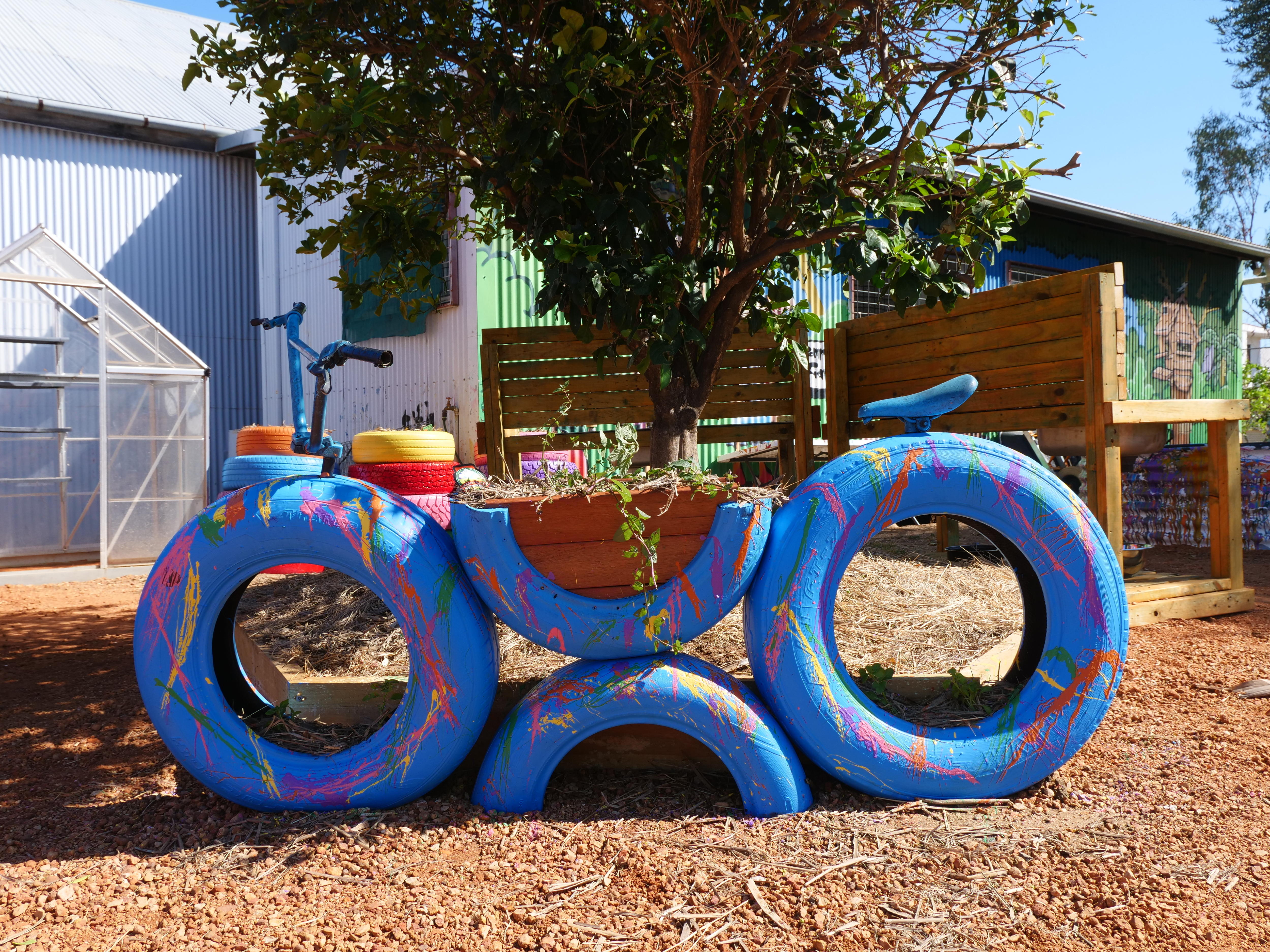 a blue planter constructed in the shape of a bicycle in a community garden