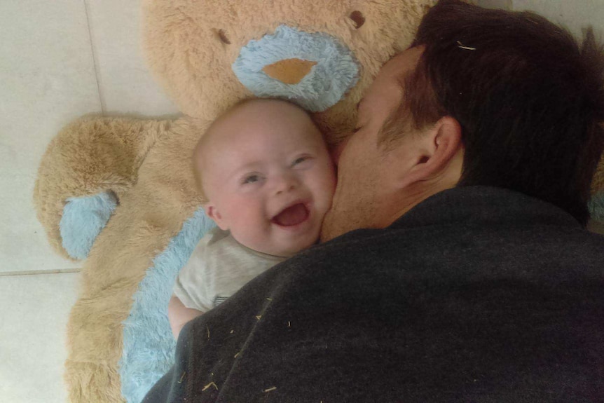 Dad enjoys cuddles with baby Xavier on bear rug