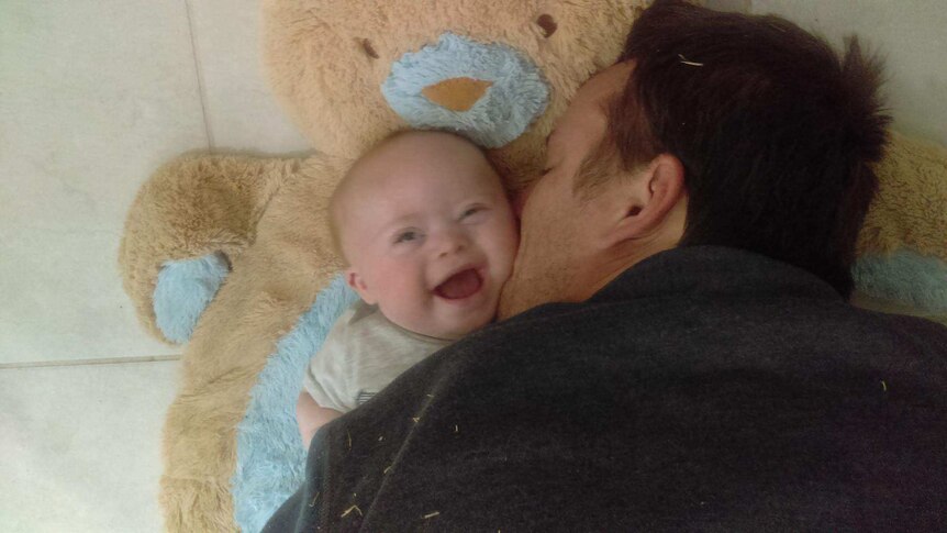 Dad enjoys cuddles with baby Xavier on bear rug