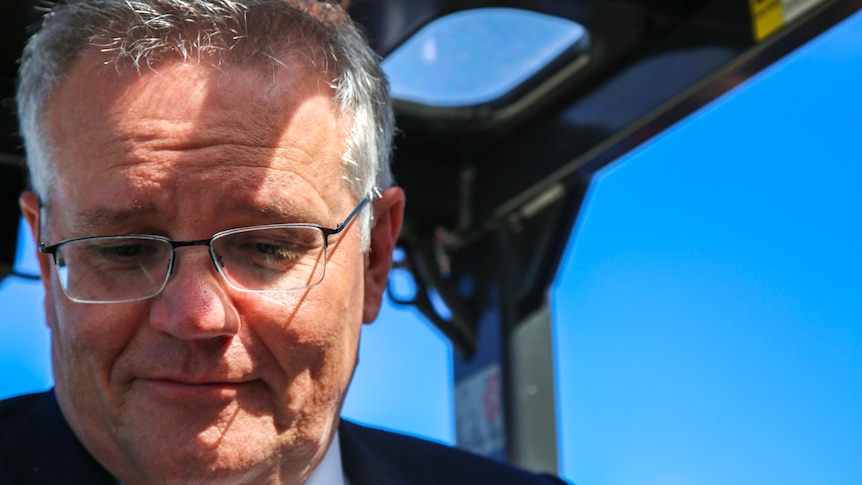 Scott Morrison looks down while sitting in a forklift