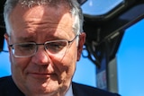Scott Morrison looks down while sitting in a forklift