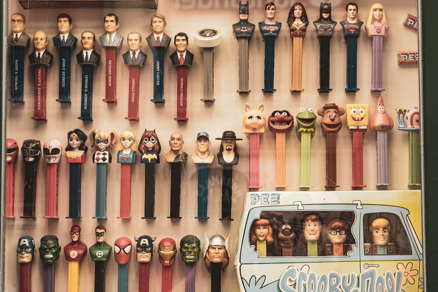 A collection of Pez dispensers, including Scooby Doo and superhero figures, on display.