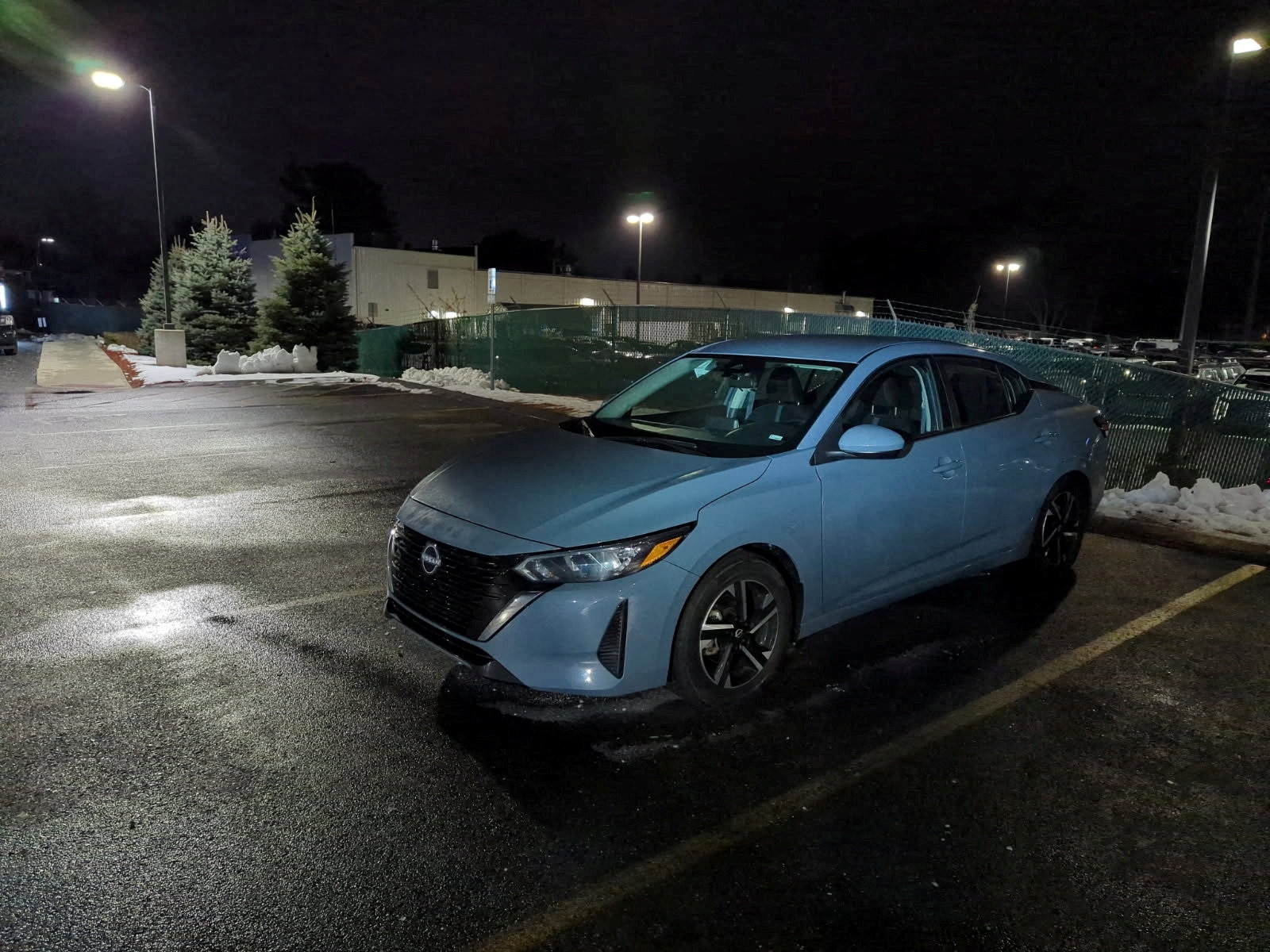 Un automóvil Nissan gris estacionado por la noche.