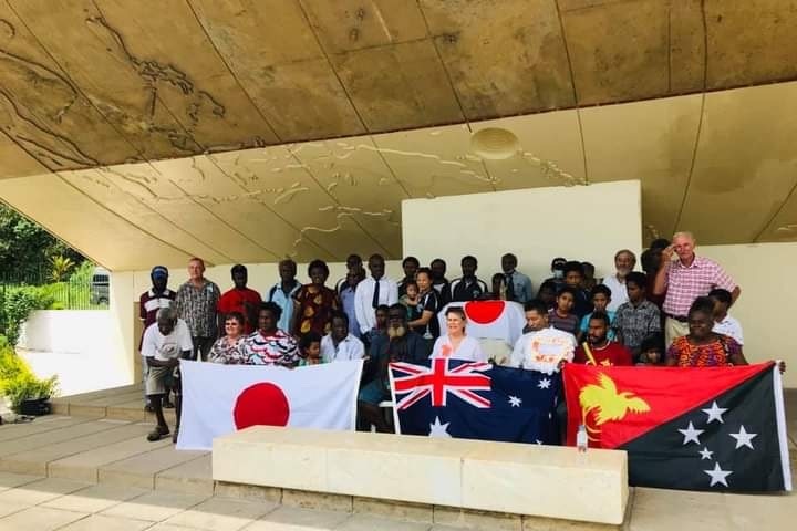 Members of the Rabaul Historical Society and Rabaul community leaders stand with Japan and PNG flags at the ceremony.