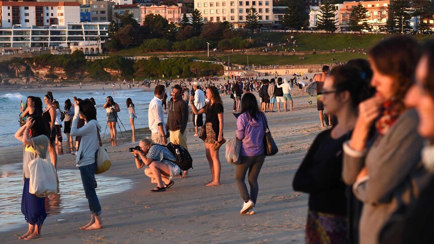 Revellers cover Bondi Beach as the first rays of daylight break.