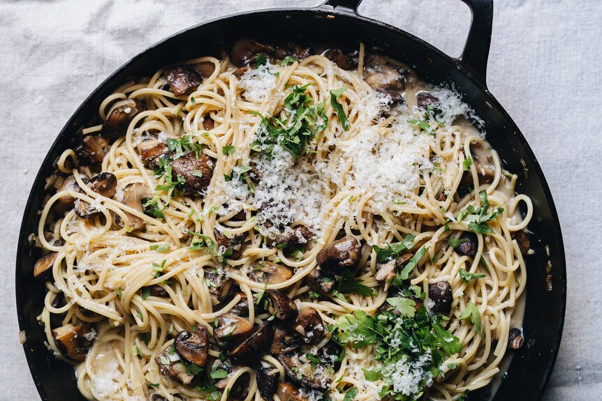 Saucepan full of vegetarian carbonara with mushrooms, miso paste, topped with cheese and parsley, a dinner pasta recipe.
