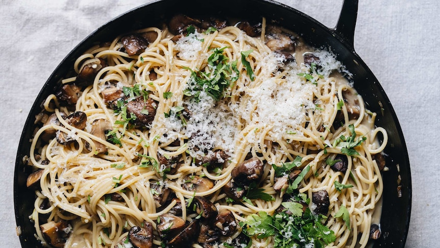 Saucepan full of vegetarian carbonara with mushrooms, miso paste, topped with cheese and parsley, a dinner pasta recipe.