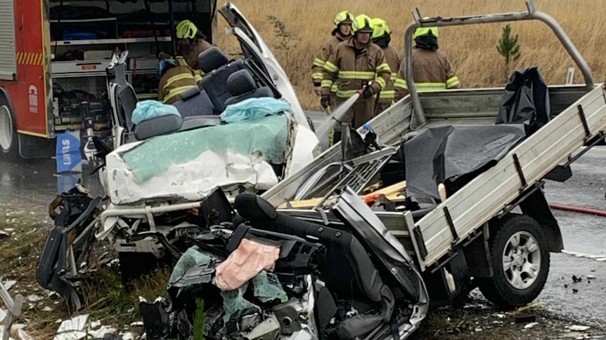 Two wrecked vehicles on the side of a country road. A fire truck and firefighters are in the background