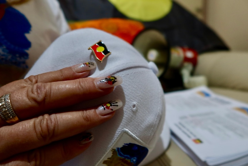A woman with Aboriginal designed nails and a hat.
