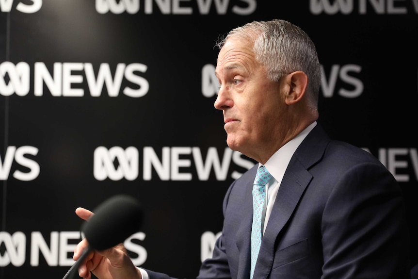 Malcolm Turnbull, in profile, looking stern and pointing  a finger while speaking into a microphone in an ABC studio.