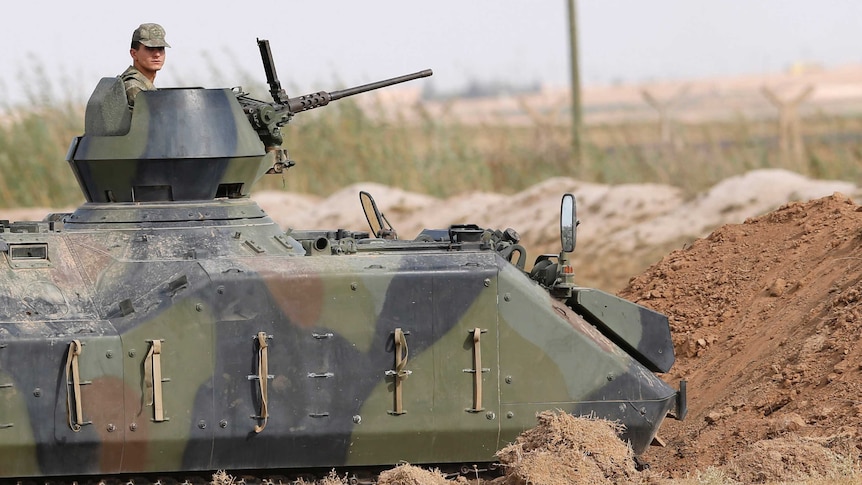 A Turkish soldier stands guard in an armoured personnel carrier