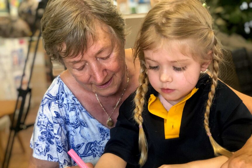Four-year-old girl draws a picture with elderly woman
