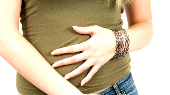 A woman with her hand on her stomach and another across her groin, in pain.