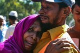 A woman in tears hugs a man, who is also crying.