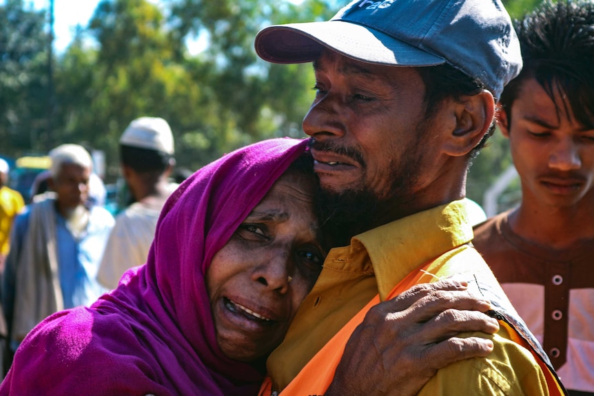 A woman in tears hugs a man, who is also crying.