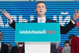 Alexei Navalny gestures while speaking during his supporters' meeting. His wife Yulia is standing to his left.