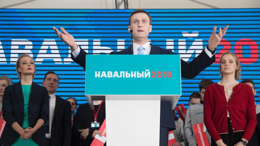Alexei Navalny gestures while speaking during his supporters' meeting. His wife Yulia is standing to his left.