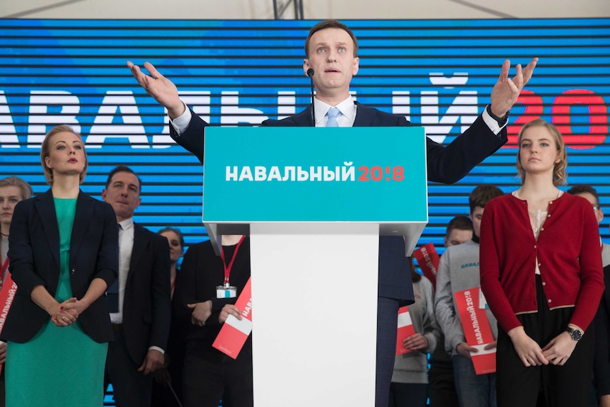 Alexei Navalny gestures while speaking during his supporters' meeting. His wife Yulia is standing to his left.