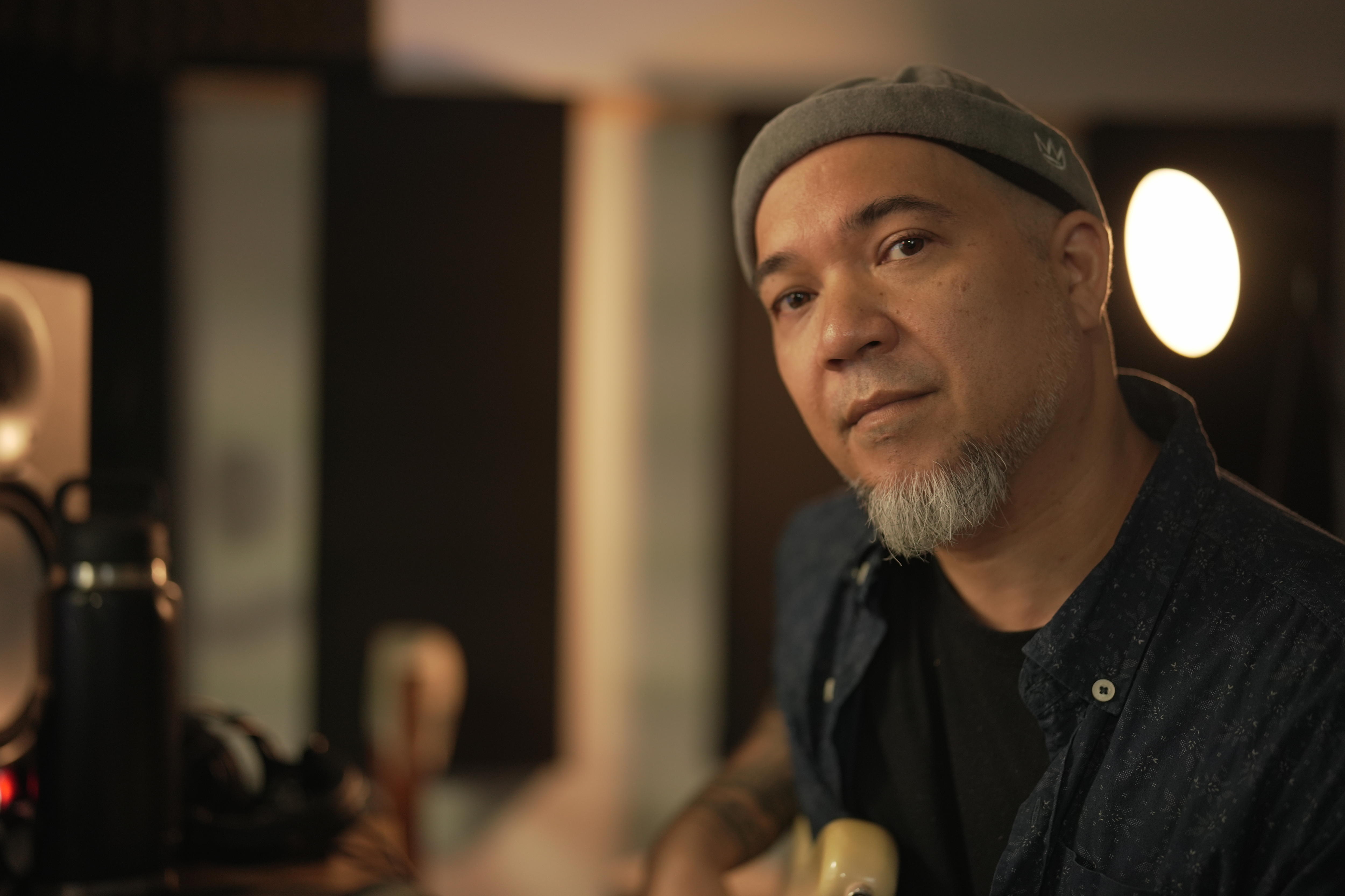 Un hombre con un gorro y una perilla sosteniendo un bajo