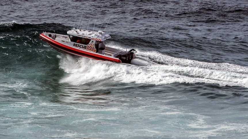 A sea rescue boat on a wave in the ocean.
