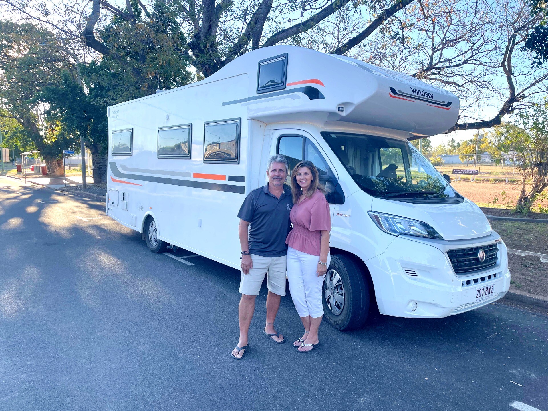 Couple standing in front of modern large white campervan