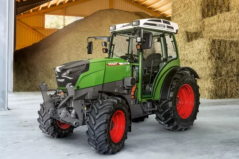 a green electric tractor prototype in a hay shed
