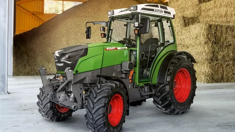 A green electric tractor prototype in a hay shed