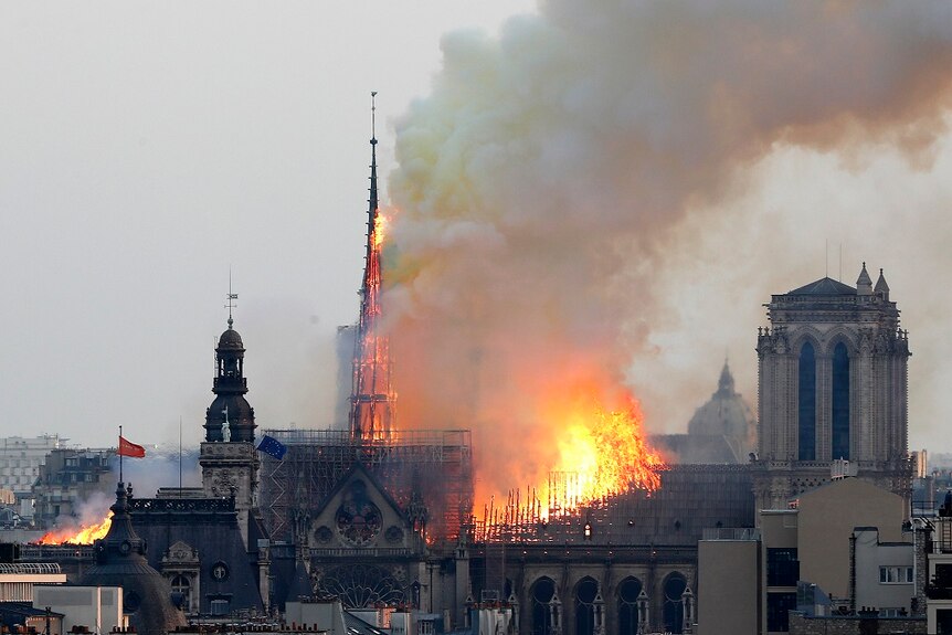 Flames burn through the spire and roof of a cathedral