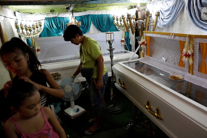 Relatives inside a room where two caskets with bodies are located.