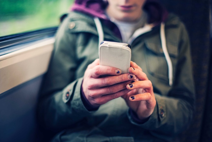 Teenage girl using her smart phone while on the train.