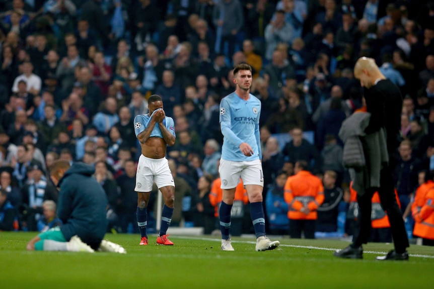 A soccer player covers his face with his shirt and the coach walks with his head down after a loss.