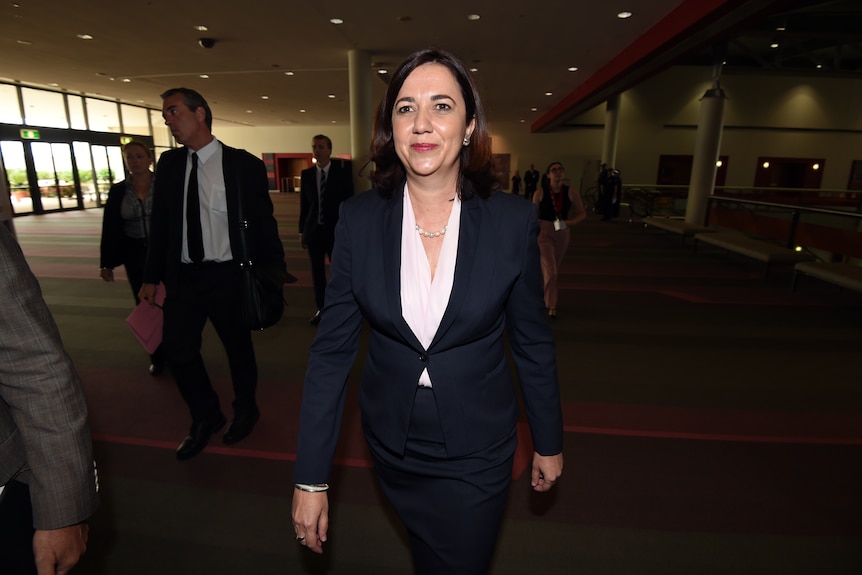 premier annastaciz palaszczuk walks through a foyer wearing a black skirt suit