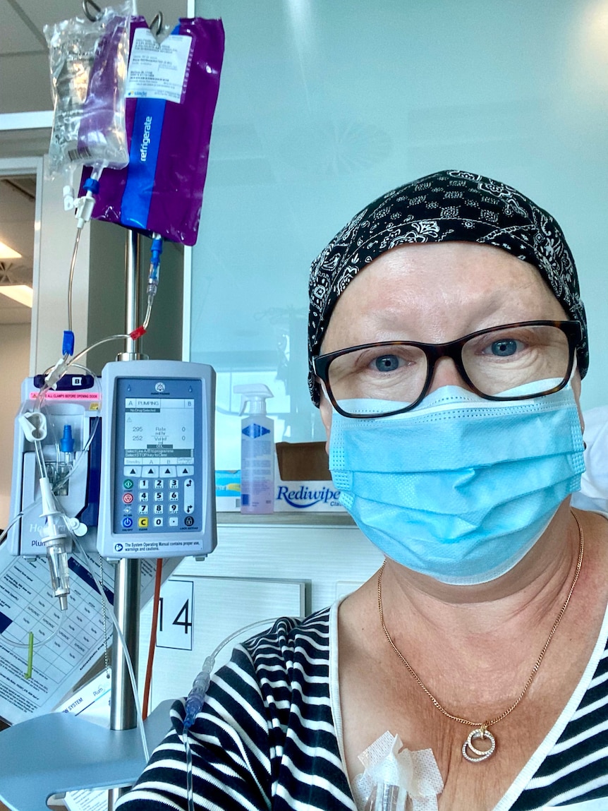 Woman wearing a face mask and bandana, receiving cancer treatment in hospital.