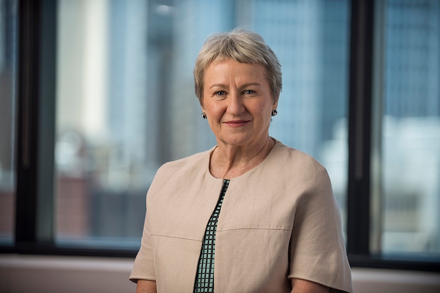 A woman with short grey hair and a bolero smiles at the camera