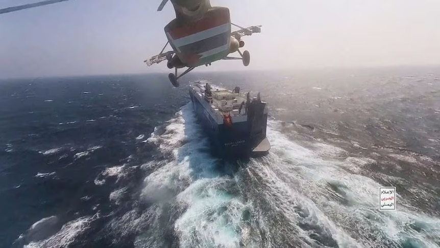 A helicopter flying above a cargo ship in the ocean