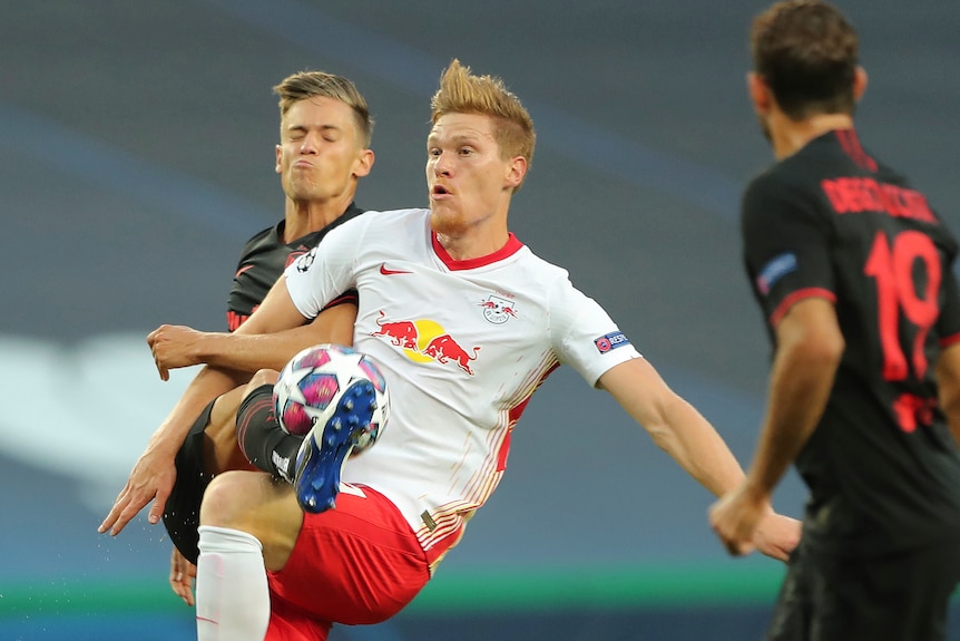 Marcel Halstenberg challenges for the ball with Marcos Llorente, who has his eyes closed