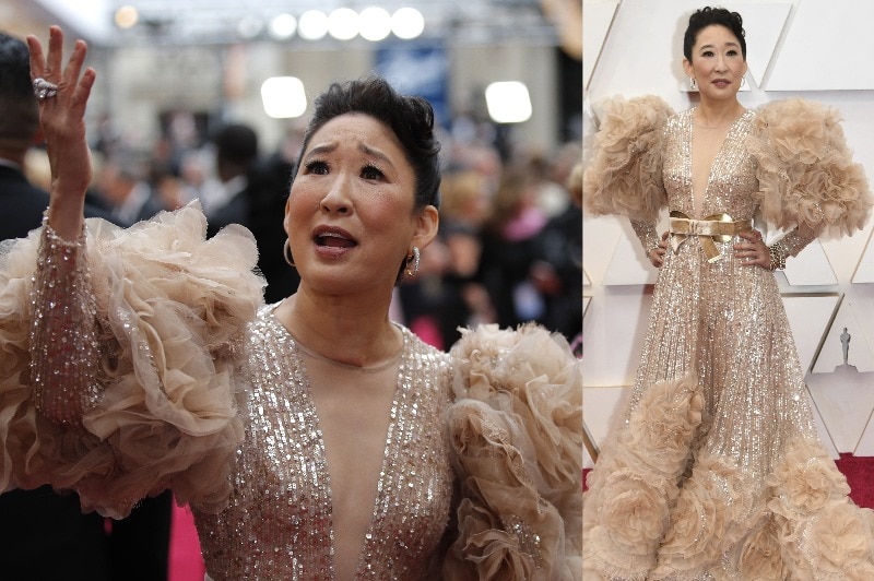 Sandra Oh wearing a golden and beige dress with large fluffy sleeves and sparkly embellishments.