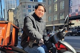 A man on a motorbike parked at a sidewalk at Melbourne CBD